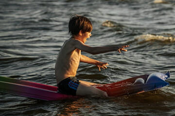 A boy riding an inflatable raft in the waves at the beach, capturing a moment of fun and adventure...