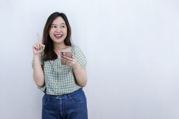Inspired young Asian woman holding smartphone and pointing finger up, creating genius solutions isolated on white background
