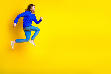 Photo of cheerful optimistic man wear trendy blue clothes jump up empty space isolated on yellow color background