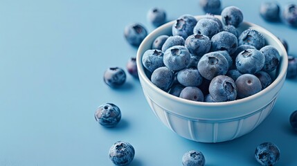 Top view of a bowl filled with fresh, tasty blueberries against a light blue backdrop, providing copy space image