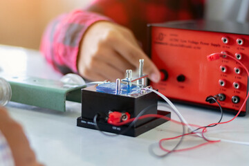 Children are studying the measurement of friction force with a spring balance using a small electric meter, small model car with a long white strip of paper to experiment with in physics science class