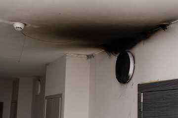 Burnt out LED lamp. A lampshade lamp on the wall after a fire. Spontaneous combustion and fire in a residential building. Fire alarm sensor indoor incident