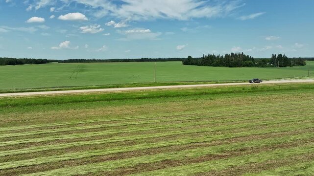 Slow motion drone shot of a pickup truck driving down a rural gravel road making a dust cloud