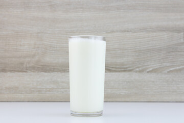 Glass of fresh milk on blurred wooden wall background