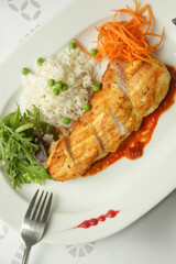 Pan fried chicken fillet served in tomato sauce with rice and fresh vegetables
