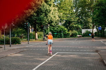 A girl with blonde hair riding a colorful scooter in a city park, capturing the joy of outdoor activities.