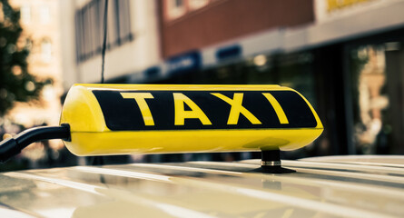 Yellow taxi sign in old historical town closeup. Cab service on city blurred background