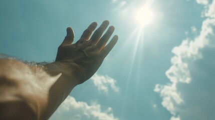 A person's hand reaches up to the sky, with the sun shining in the background