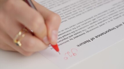 Professional school or college teacher grades a homework exam papers of students. Woman grades test with 92 percent and writes great as comment.