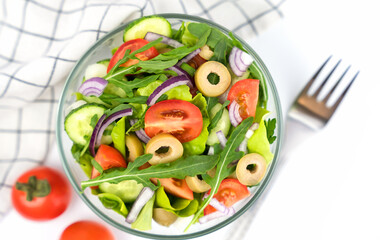 A portion of healthy and tasty salad made from fresh vegetables, olives and arugula. Top view. Selective focus.
