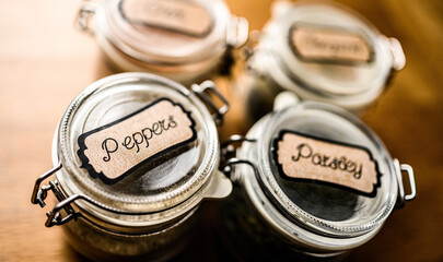 Set of different spicies in glass jars at the kitchen. Black pepper and dried greens.