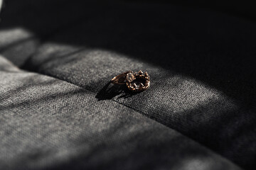 Obraz premium A ring is sitting on a gray surface. The ring is made of gold and has a design on it