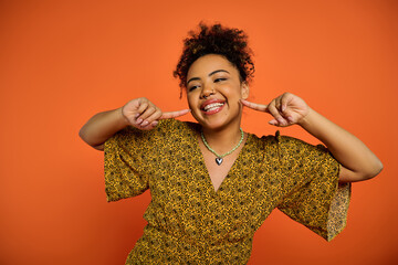 African American woman in stylish attire making a silly face with her fingers.