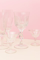 Empty crystal glasses in front of pink background. Creative concept.