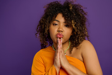 Stylish African American woman in orange top gestures confidently.