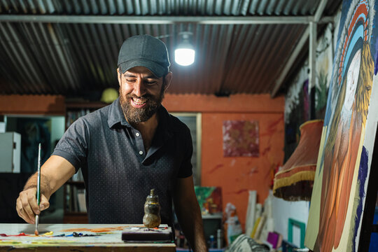 Joyful Latin American artist painting in his studio
