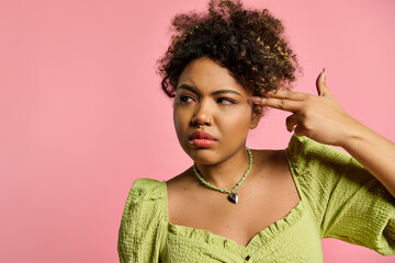 A stylish African American woman in a yellow top listens intently by placing her hand on her ear.