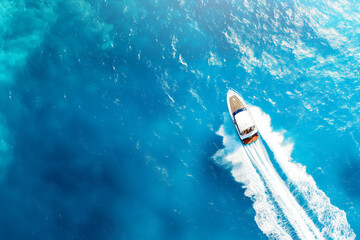 Obraz premium Aerial shot. The image of a speedboat speeding through the blue sea, the splash of the boat's path, full of energy and peace.