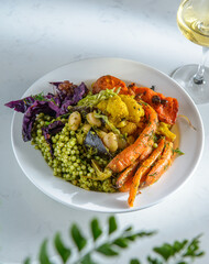 Top view of a bowl prepared with a variety of greens, vegetables and beans on a white table. Healthy food. Vegan, vegetarian food.