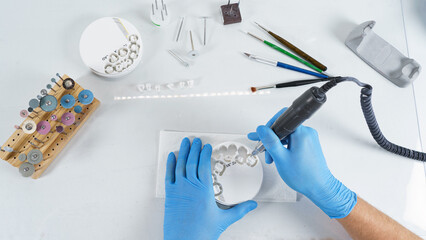 dental technician processes a zircon tablet with milled crowns, on a table with different tools © Dental Pro Content