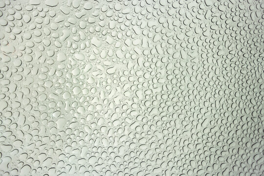 Abstract image of waterdrops viewed from beneath glass car roof, many water droplets in circular pattern, texture