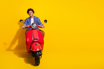 Full size photo of positive man dressed striped shirt in helmet driving motorcycle near empty space isolated on vivid color background