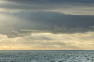 Seascape showing cloudy sky above sea, space for text, winter sunny day, UK England