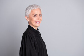 Photo of smiling judge senior woman look profile side wear black robe isolated grey color background