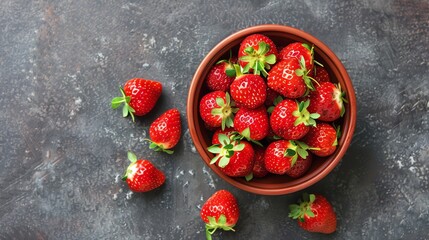 A bowl of fresh strawberries on a gray background.