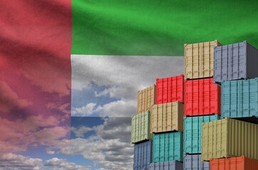 United Arab Emirates flag and big stack of shipping cargo containers in docks with sky background close up