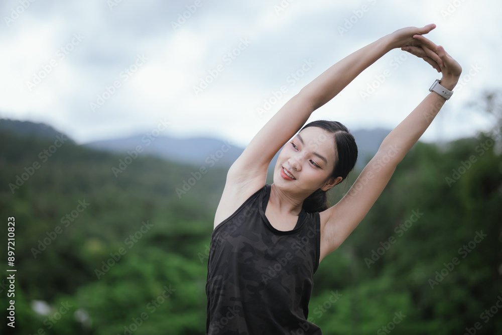 Wall mural a young, beautiful asian woman runs happily in a city park on a summer morning. embracing an active 