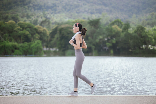 A beautiful woman jogs alone in the city, drinking water. Embracing an active lifestyle, she runs with energy and joy, showcasing fitness, health, and endurance, enjoying the outdoors and nature's bea