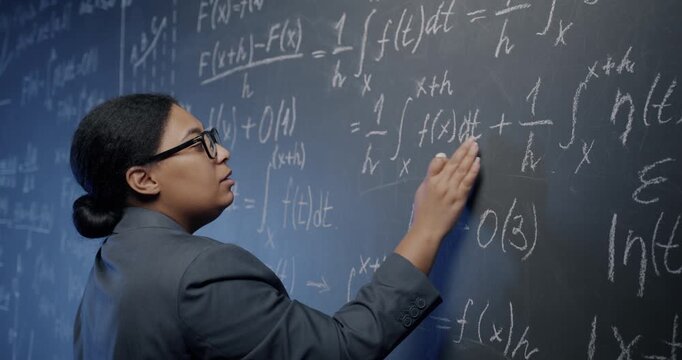 African American woman algebra teacher explaining formula writing and speaking teaching in class at school. Modern education and science concept.