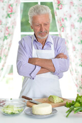 Happy retired senior man cooking in kitchen. 