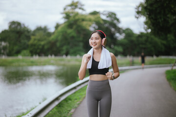 A beautiful young Asian woman, running in the city, embodies an active lifestyle. This joyful athlete, wearing sportswear and earphones, trains with energy and motivation, enjoying a healthy, powerful