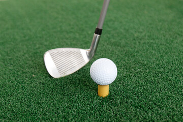 Golf ball on tee and club on grass. Ready to shot. Golf green lawn background. Space for text