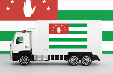 Abkhazia flag depicted on side wall of white delivery van close up. Shipping and local delivery concept