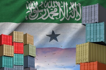 Somaliland flag and big stack of shipping cargo containers in docks with sky background close up