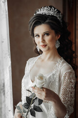 A woman wearing a white gown and a tiara holding a rose. Concept of elegance and sophistication, as...
