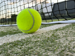 Tennis or paddle balls on synthetic grass of paddle court with net on the background