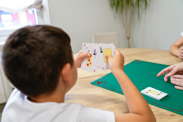 A young boy is playing a card game with his family