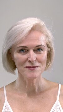 Portrait: beautiful pretty old blonde woman with blue eyes. Senior female looks at the camera, smiling with white teeth. Elderly retired beauty care, healthy dry skin. Cosmetics, plastic surgery