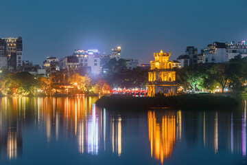 Turtle Tower in Hoan Kiem lake. Illuminated Old quarter in Hanoi at night, Vietnam..