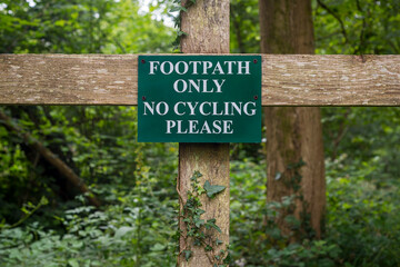 Footpath only, no cycling please sign on a wooden fence in the countryside