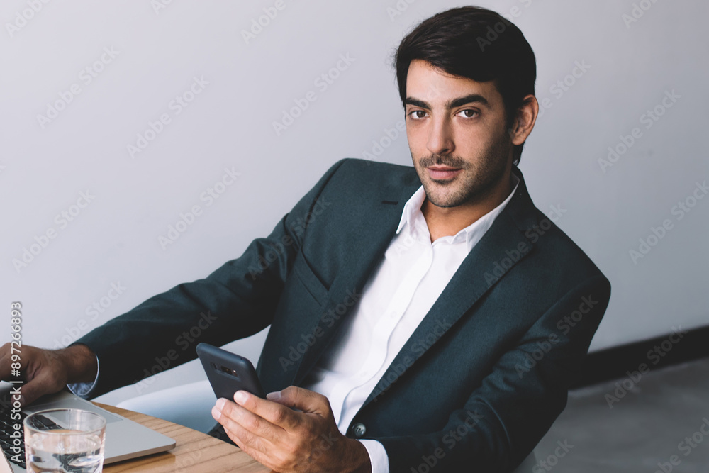 Poster portrait of concentrated indian computer expert looking at camera and waiting colleague for meeting 