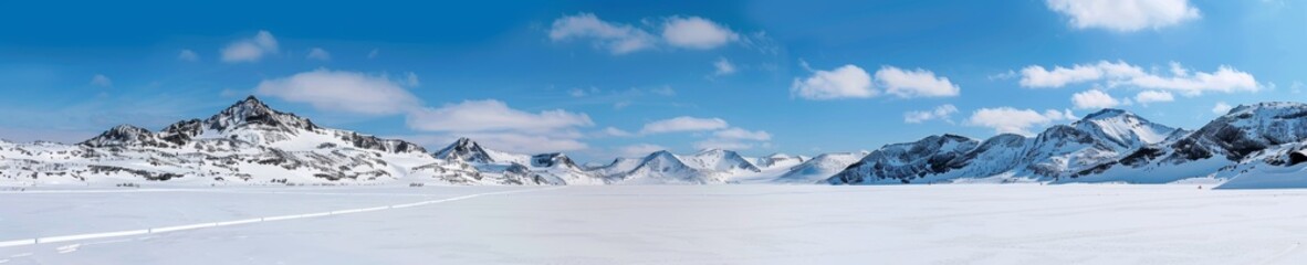 Obraz premium panoramic winter landscape with snow covered mountains, blue sky and fluffy clouds, ideal for travel, nature, and winter backgrounds.