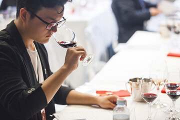 Asian Sommelier Tasting Red Wine during Participation in International Competition of Wine Experts