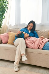 Obraz premium An Asian mother and her teenage daughter sit atop a couch, enjoying a cozy moment at home.
