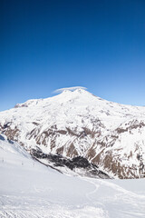Obraz premium Snowy mountain peaks of Elbrus and nearby peaks in winter on a sunny day 