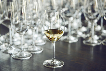 Glas of white wine on table against empty bokals background. Alcholic beverages tasting. 